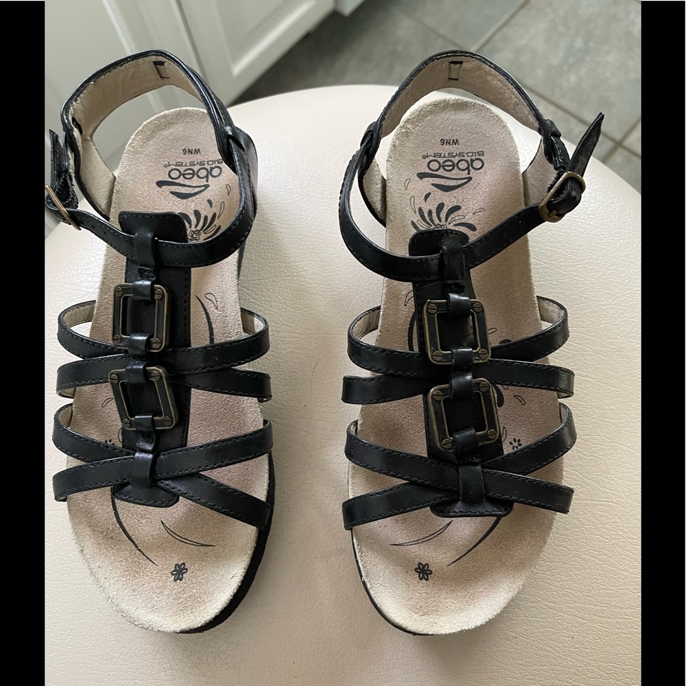 Abeo black sandals with 1.5” heels and a decorative embellishment.